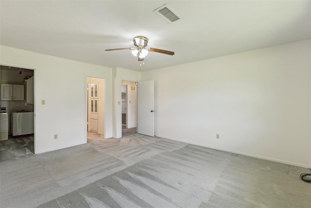 2525 NW 62nd St Unit 208, Oklahoma City, OK 73112 - unfurnished bedroom featuring light carpet, baseboards, connected bathroom, washer and dryer, and a ceiling fan
