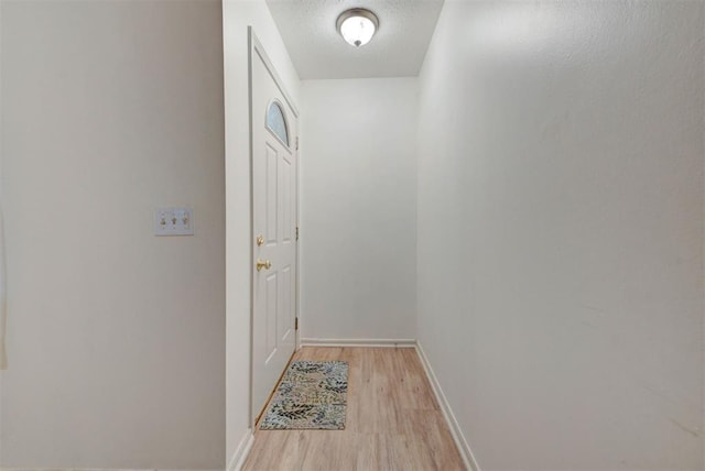 entryway featuring light wood-type flooring, baseboards, and a textured ceiling