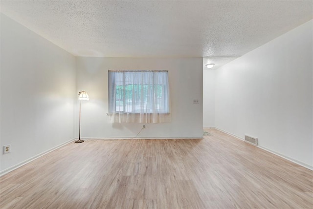 unfurnished room featuring a textured ceiling, wood finished floors, and baseboards