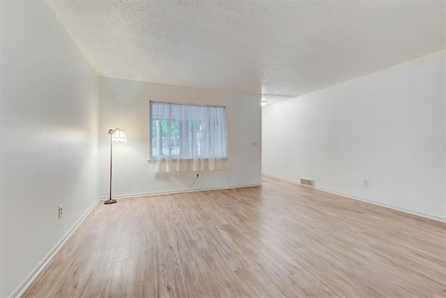 unfurnished living room with a textured ceiling, wood finished floors, and baseboards