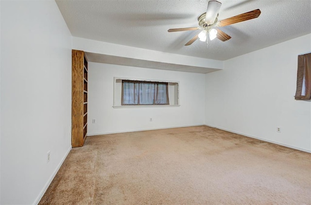carpeted empty room featuring a ceiling fan, a textured ceiling, and baseboards