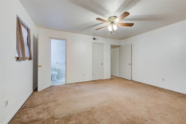 unfurnished bedroom featuring carpet floors, a textured ceiling, ensuite bathroom, baseboards, and ceiling fan