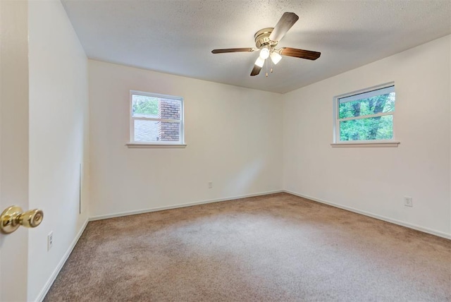 carpeted spare room featuring healthy amount of natural light, a ceiling fan, and baseboards