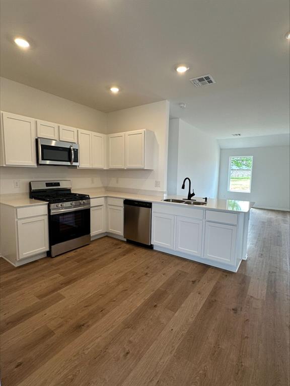 866 SW 11th St, Newcastle, OK 73065 - kitchen featuring stainless steel appliances, a sink, wood finished floors, white cabinets, and recessed lighting