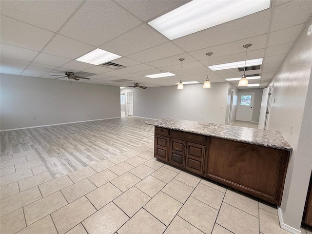 312 N 6th St, Amber, OK 73004 - kitchen with a ceiling fan, a paneled ceiling, decorative light fixtures, dark brown cabinetry, and light stone counters