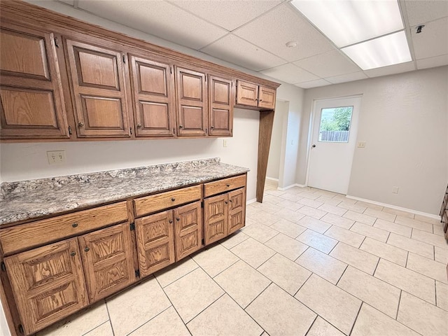 312 N 6th St, Amber, OK 73004 - kitchen with brown cabinetry, light tile patterned floors, baseboards, a paneled ceiling, and light countertops