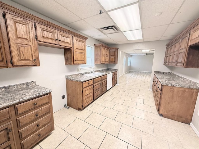 312 N 6th St, Amber, OK 73004 - kitchen featuring white dishwasher, a sink, brown cabinetry, a paneled ceiling, and light tile patterned flooring