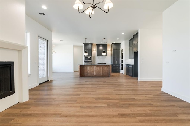 9213 NW 85th St, Yukon, OK 73099 - kitchen featuring open floor plan, a chandelier, dark countertops, light wood-type flooring, and a fireplace