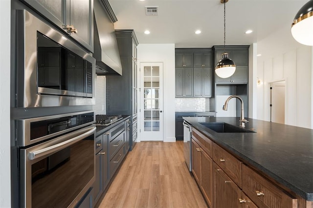 9213 NW 85th St, Yukon, OK 73099 - kitchen featuring stainless steel appliances, a sink, island exhaust hood, decorative backsplash, and light wood-style floors
