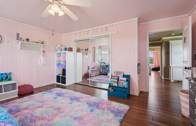 7941 E Sorghum Mill Rd, Edmond, OK 73034 - bedroom featuring ornamental molding, wood-type flooring, a ceiling fan, a closet, and wooden walls
