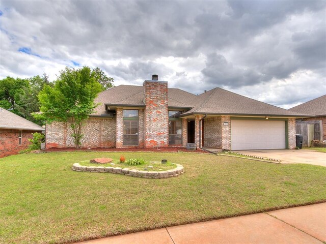 view of front of property featuring driveway, brick siding, an attached garage, a front yard, and a chimney
