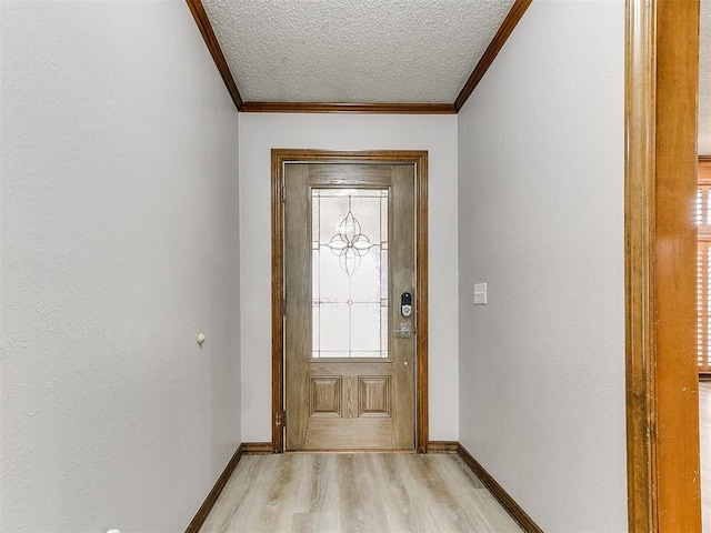 entryway with ornamental molding, light wood finished floors, a textured ceiling, baseboards, and a textured wall