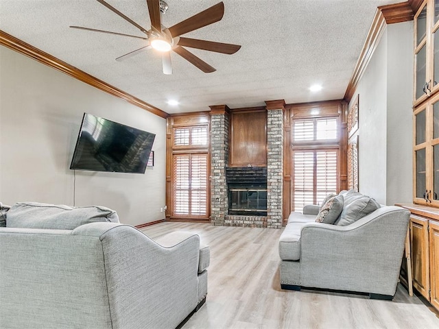living area featuring ornamental molding, a ceiling fan, plenty of natural light, light wood-type flooring, and a textured ceiling