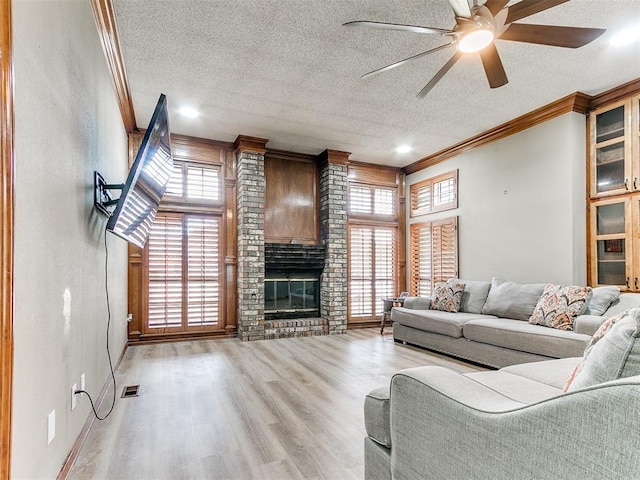 living area featuring ornamental molding, ceiling fan, wood finished floors, a textured ceiling, and a brick fireplace