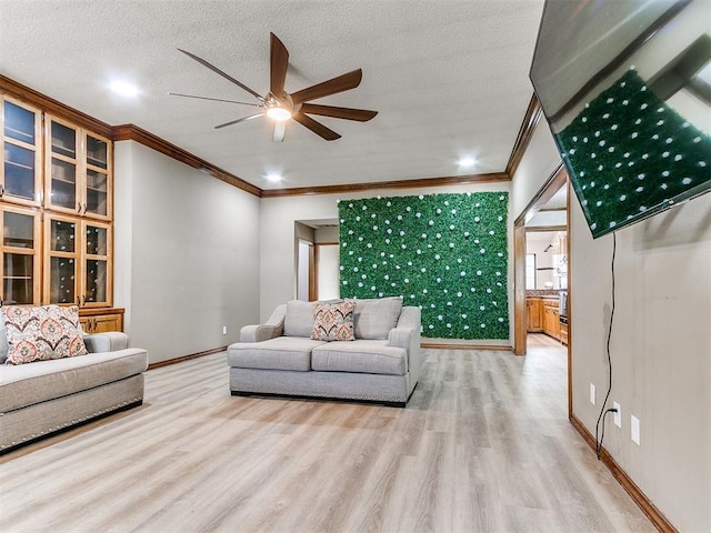 living area featuring crown molding, a ceiling fan, wood finished floors, baseboards, and a textured ceiling