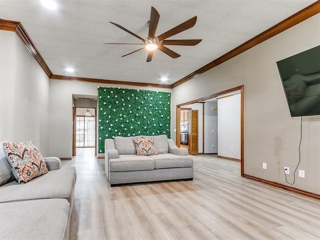 living room featuring ornamental molding, ceiling fan, wood finished floors, baseboards, and a textured ceiling