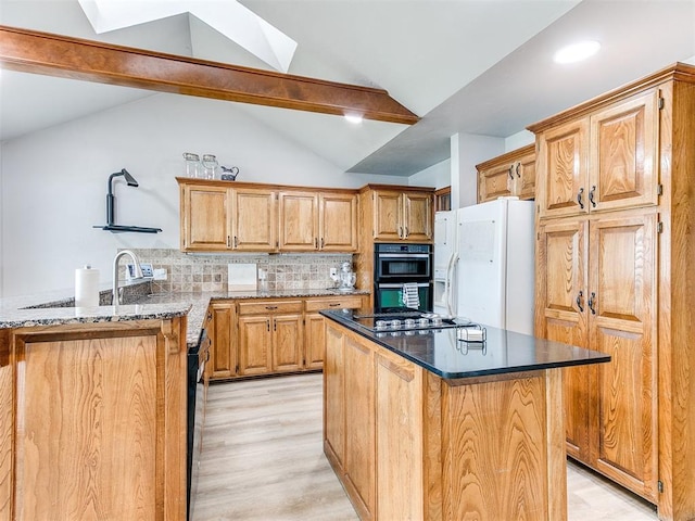 kitchen with black appliances, light wood-type flooring, decorative backsplash, a kitchen island, and a skylight