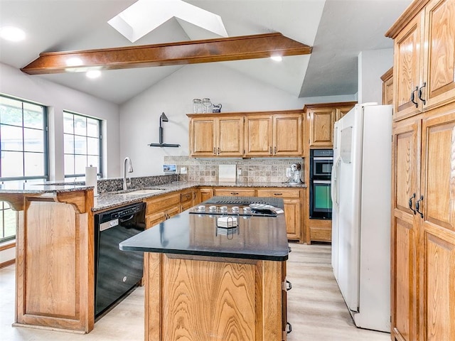 kitchen featuring black appliances, a sink, a skylight, a peninsula, and a breakfast bar