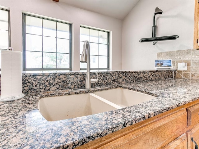 kitchen view of a sink and dark stone countertops