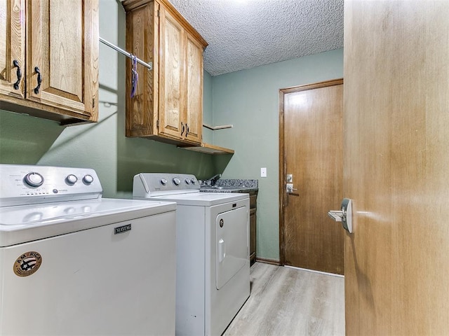 washroom featuring cabinet space, independent washer and dryer, light wood-style floors, and a textured ceiling