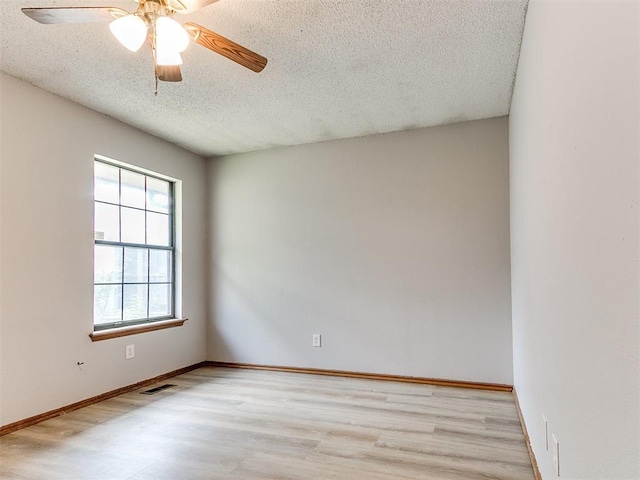 empty room featuring a textured ceiling, wood finished floors, ceiling fan, and baseboards