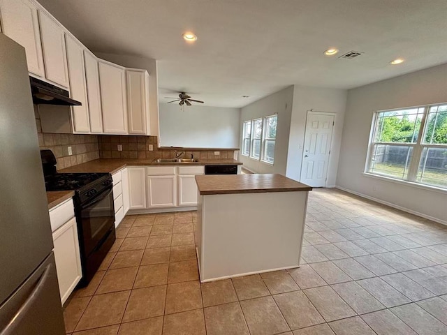 1918 W K Ct, Jenks, OK 74037 - kitchen with black gas stove, freestanding refrigerator, under cabinet range hood, light tile patterned floors, and recessed lighting