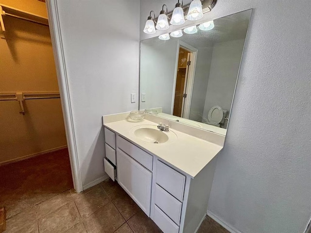 1918 W K Ct, Jenks, OK 74037 - bathroom featuring a spacious closet, vanity, tile patterned floors, baseboards, and a textured wall