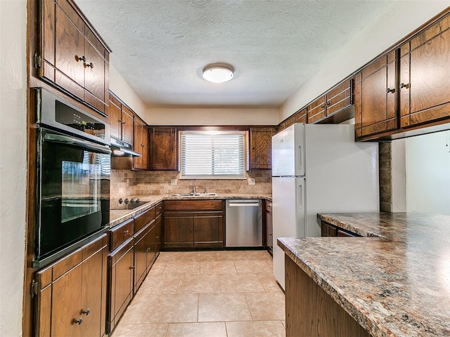 kitchen featuring black appliances, a sink, under cabinet range hood, tasteful backsplash, and a textured ceiling