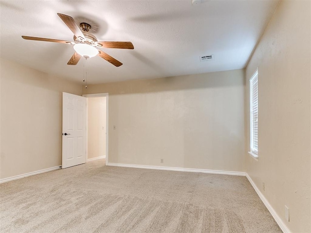 carpeted empty room with ceiling fan and baseboards