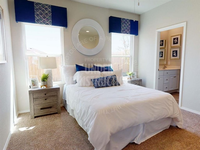 carpeted bedroom with ensuite bath and baseboards