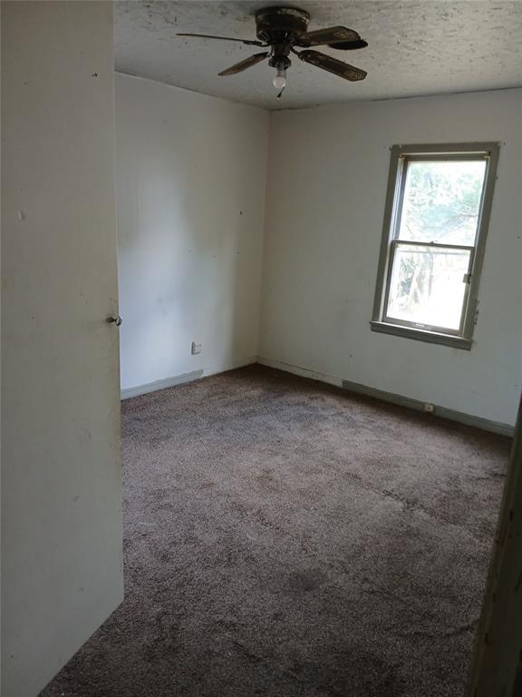 carpeted empty room featuring a ceiling fan, a textured ceiling, and baseboards