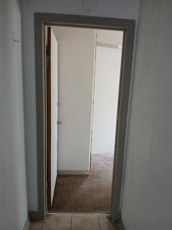 corridor featuring carpet floors, tile patterned flooring, and baseboards