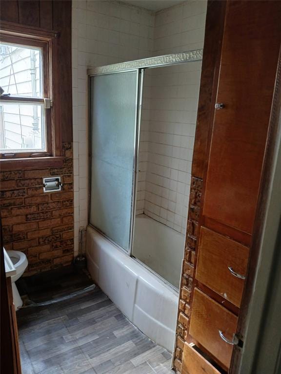 bathroom featuring enclosed tub / shower combo and toilet