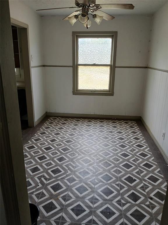 unfurnished room featuring a ceiling fan and baseboards