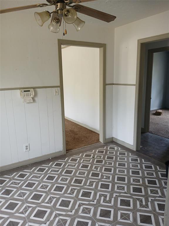 unfurnished bedroom with wainscoting and a ceiling fan