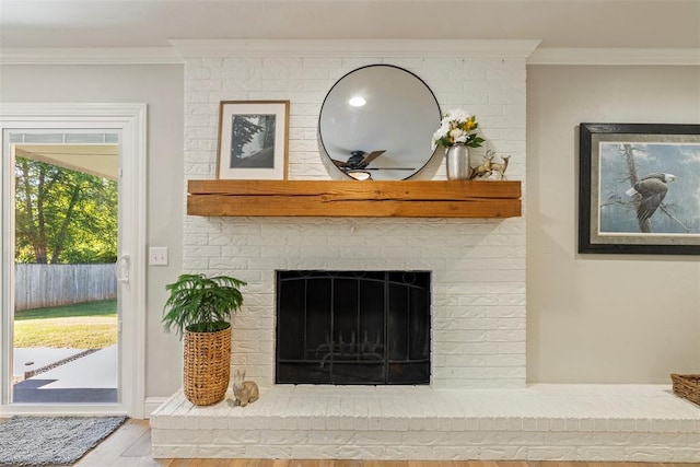 detailed view of wood finished floors, crown molding, and a brick fireplace