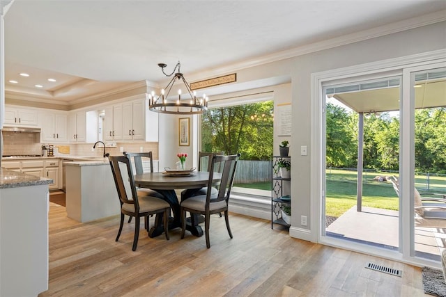 dining space with a chandelier, light wood finished floors, ornamental molding, and recessed lighting