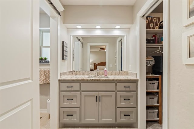 full bath with connected bathroom, vanity, a spacious closet, and ceiling fan