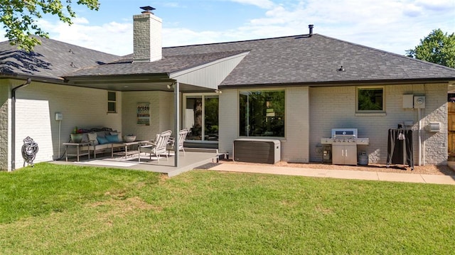 rear view of property featuring roof with shingles, an outdoor living space, a patio area, a chimney, and a lawn