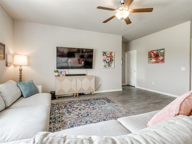 living area with wood finished floors, a ceiling fan, and baseboards