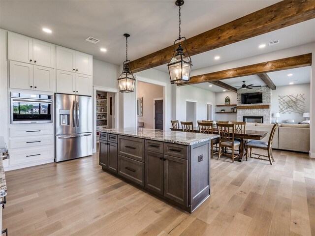 3241 E 171st St, Bixby, OK 74008 - kitchen featuring appliances with stainless steel finishes, light wood finished floors, a stone fireplace, beamed ceiling, and light stone counters