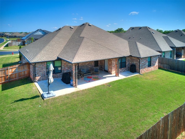 rear view of house with a patio, a shingled roof, and brick siding
