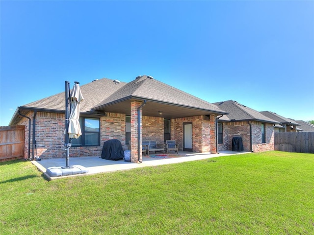 back of property with a patio area, brick siding, and roof with shingles
