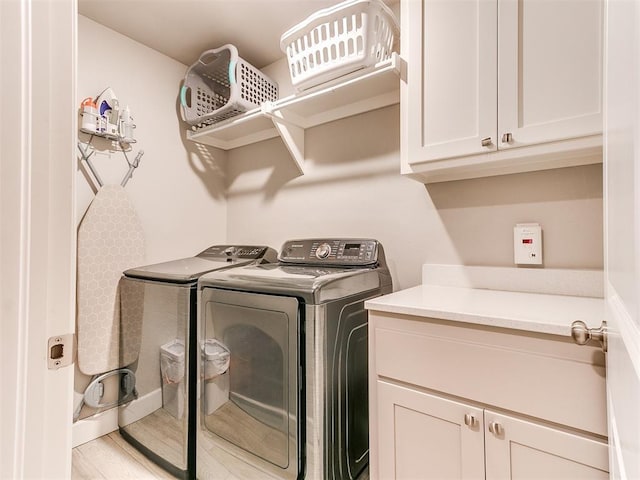 laundry area featuring washing machine and clothes dryer, cabinet space, and wood finished floors