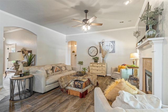13141 Austrian Pine Dr, Choctaw, OK 73020 - living area featuring arched walkways, wood finished floors, a tiled fireplace, ceiling fan, and crown molding