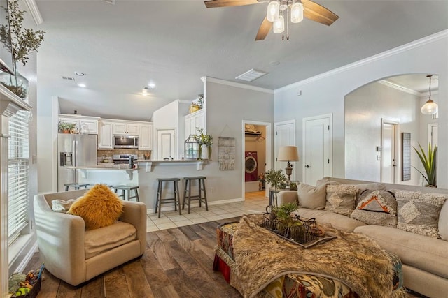 13141 Austrian Pine Dr, Choctaw, OK 73020 - living area with arched walkways, light wood-style flooring, a ceiling fan, ornamental molding, and washer / dryer
