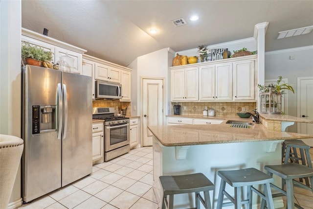 13141 Austrian Pine Dr, Choctaw, OK 73020 - kitchen with appliances with stainless steel finishes, a sink, a kitchen breakfast bar, backsplash, and a peninsula