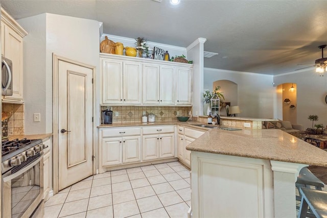 13141 Austrian Pine Dr, Choctaw, OK 73020 - kitchen featuring a sink, gas range, a kitchen bar, ceiling fan, and backsplash