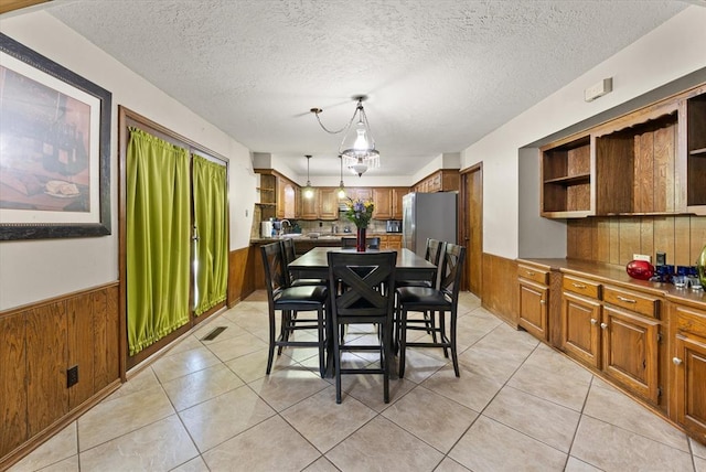 3926 Briarcrest Dr, Norman, OK 73072 - dining room featuring a wainscoted wall, wood walls, a textured ceiling, and light tile patterned floors