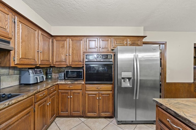 3926 Briarcrest Dr, Norman, OK 73072 - kitchen with black appliances, brown cabinetry, dark stone countertops, light tile patterned flooring, and tasteful backsplash